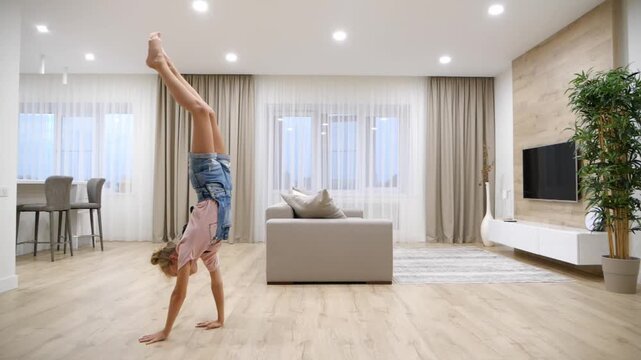 Preteen girl standing upside down on her arms in living room