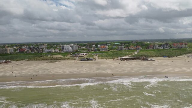 Noordwijk Beach, Noordwijk, South Holland, Netherlands, revealing the sandy shoreline, beach clubs, North Sea surf, coastal dunes, seaside resort and beachgoers, drone parallax pullback.