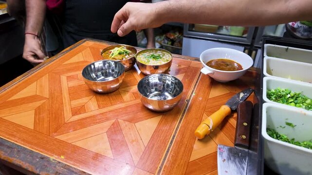 Chef Garnishing Indian Curry Bowls at Street Food Stall in Bangkok