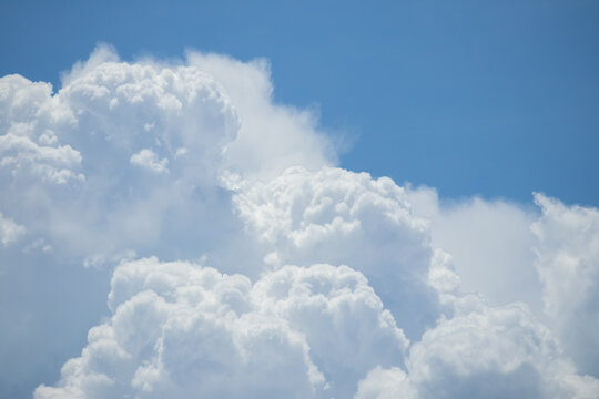 fluffy white clouds building up in the light blue sky