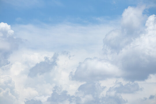 fluffy white clouds building up in the light blue sky