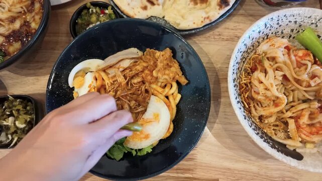 Overhead View of Person Adding Lime to Burmese Nan Gyi Tote Noodle Salad