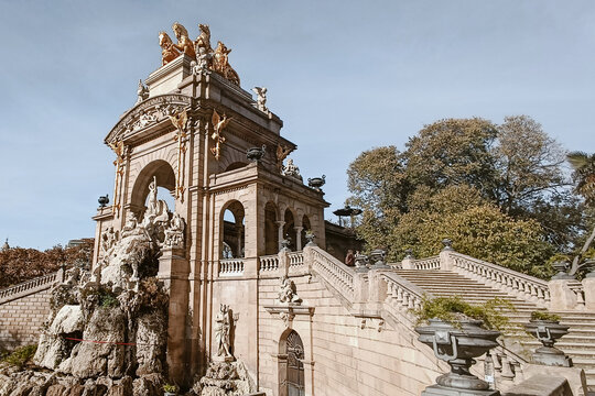 Barcelona, Spain - 06 December 2025: View of the Cascada Monumental in Parc de la Ciutadella, featuring ornate stone architecture, golden sculptures, and fountain under a clear sky.