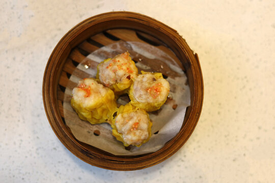 Yellow Shumai dumplings served hot in a bamboo dim sum basket.