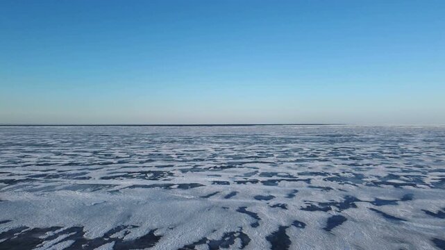 Flying at a low altitude over a iced over frozen Lake St. Clair, a minor Great Lake on the border of Michigan, United States and Ontario, Canada in winter. A popular spot for winter recreation.