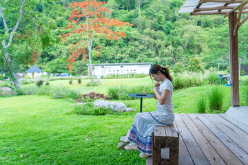 Fototapeta premium Woman Sitting on a Wooden Deck in a Green Garden”