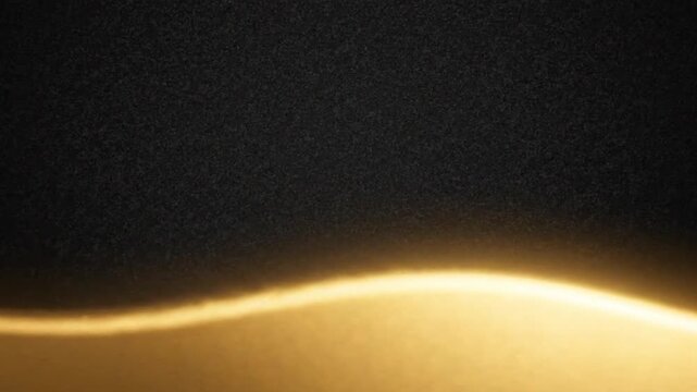 Glowing golden wave moving across a textured dark background in this smooth seamless loop animation perfect for abstract motion design