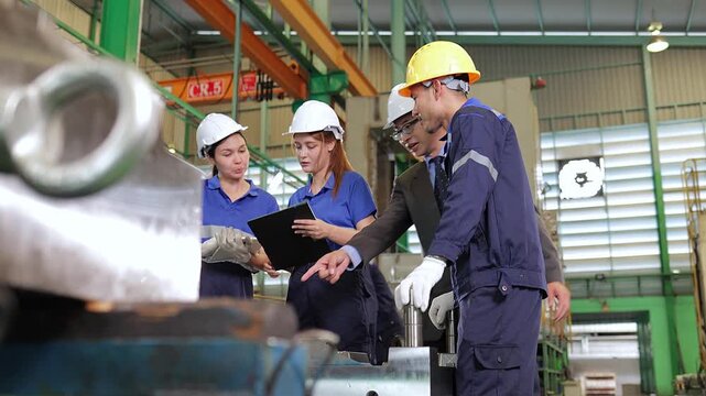 Diverse team of mechanical engineers and technicians checking machinery specifications and collaborating on a new manufacturing process inside a modern steel industrial facility.