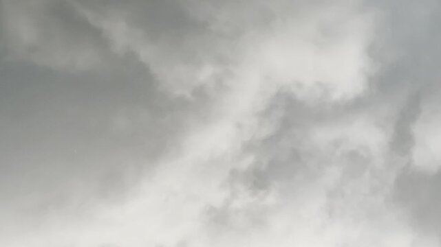 Rain falling from overcast cloudy sky video footage. Heavy rain droplets falling against dark grey storm clouds background, moody rainy weather concept