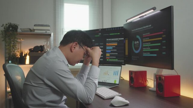 Stressed Asian Stock Trader Resting Head on Desk Facing Financial Loss. Business idea concept.