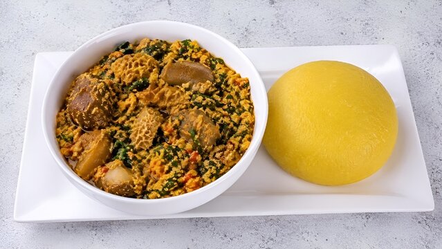 Traditional Nigerian Egusi Vegetable Soup Served with Yellow Eba (Garri)