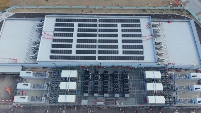 Aerial view of a hyperscale data center roof featuring industrial cooling equipment and solar panels. Suitable for technology, cloud computing, energy, and corporate infrastructure storytelling.