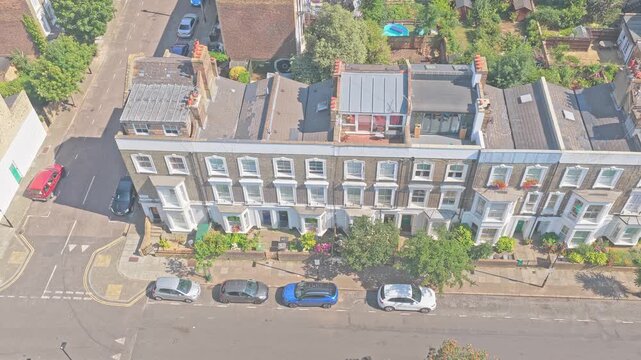 Aerial drone footage of elegant Victorian and Edwardian terraced houses near Arsenal FC's Emirates Stadium in North London, England. The aerial view captures attractive period homes, tree-lined reside