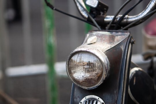 Close up side view of vintage motor scooter headlight with weathered chrome bezel