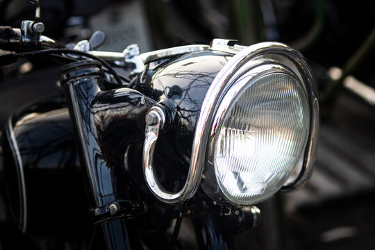 Close up view of glossy black motorcycle headlight with tubular chrome trim guard