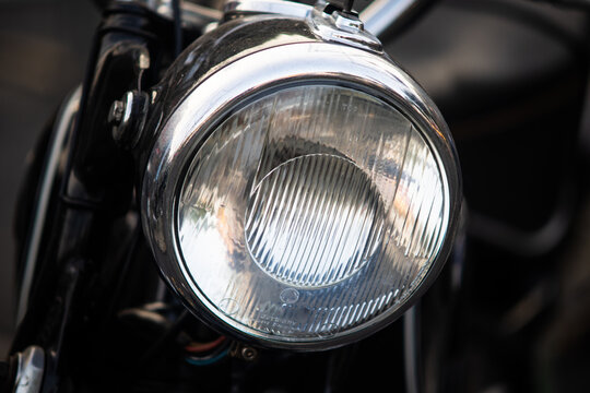 Extreme close up of vintage motorcycle glass headlight lens with shiny chrome bezel