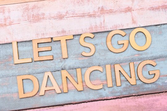 lets go dancing write on wooden background 
