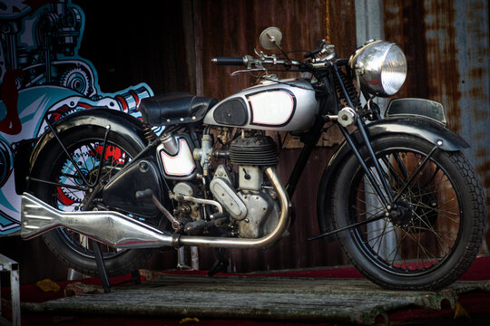 Classic vintage silver motorcycle with fishtail exhaust pipe parked indoors