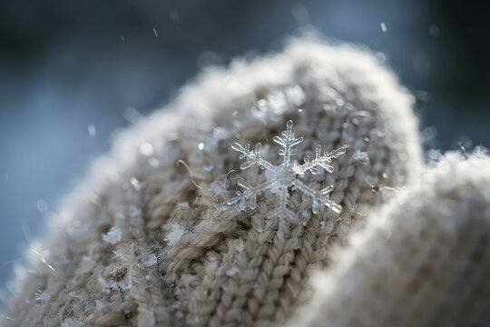 Detailed macro of a single hexagonal snowflake crystal sitting on a beige knitted wool fabric during a cold winter day