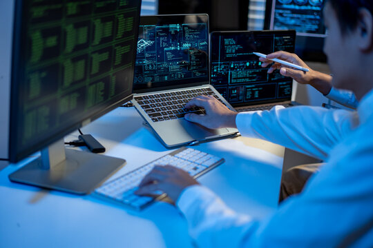 It professional analyzing code and data on multiple screens in a modern office.