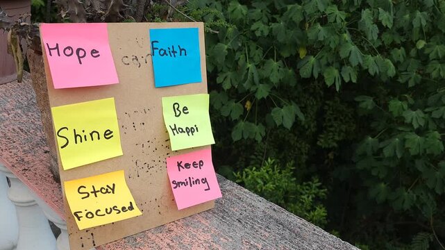 Clipboard Board with Colorful Motivational Sticky Notes Set Up Next to Garden