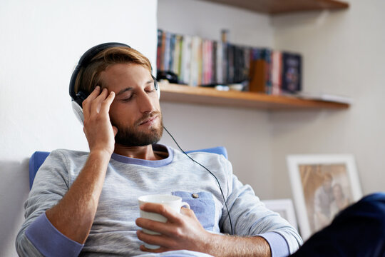Relax, coffee or man listening with headphones for music, audio streaming or comfort in home. Calm, male person or chilling with drink or sound app for weekend entertainment or song playlist in house