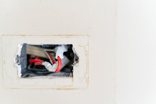 Exposed electrical wiring in a broken wall socket