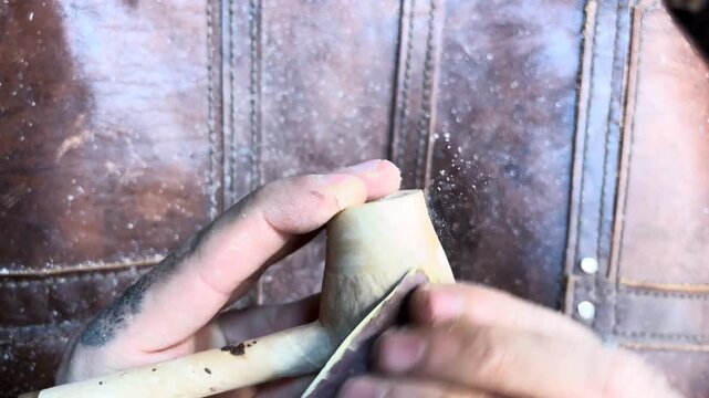 Artisan crafting a custom wooden smoking pipe by hand