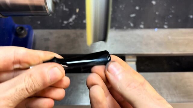 Craftsman polishing a small part on a buffing wheel