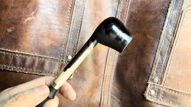 Craftsman carefully applying dark stain to a handmade wooden pipe
