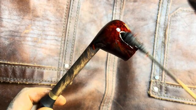 Craftsman applying a glossy varnish to a wooden pipe