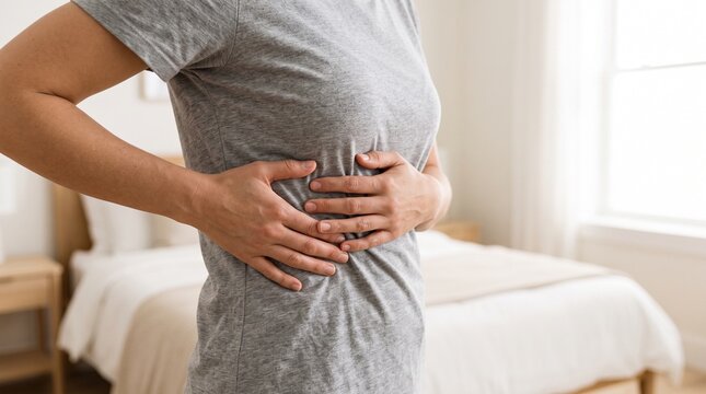 Unwell woman touching painful rib cage feeling discomfort in bedroom