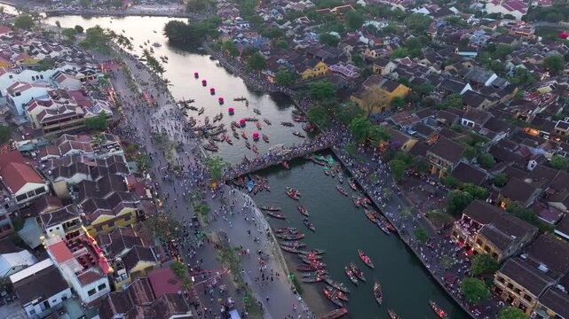 Drone view of Hoi An Ancient Town and Thu Bon River at dusk with crowded street, Vietnam