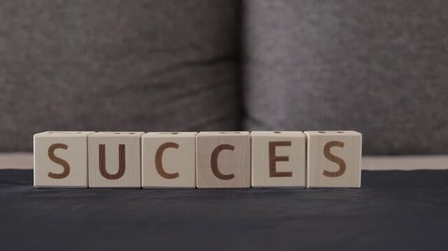 success, motivational word, laying out  by hand from letters on wooden cubes, slow motion
