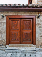 Fototapeta premium An ornate traditional wooden door with pomegranate carvings on an old stone house in the historic Kaleici district of Antalya, Turkey