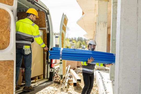 Construction workers unloading bundle of blue water pipes