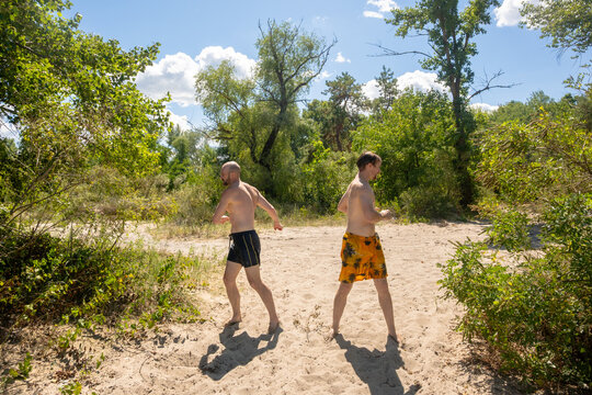 Two Friends in Swimwear Running and Having Fun on a Sandy Forest Trail in Summer