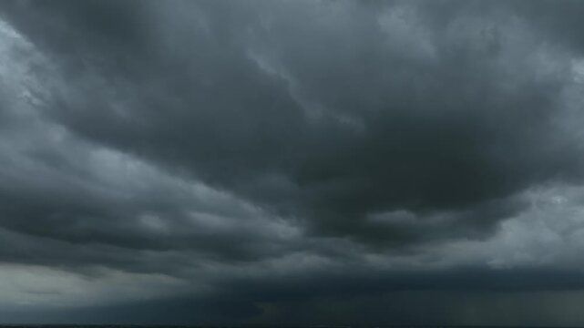 Drone view of fast drifting rainstorm clouds with massive dark formations, creating a dramatic natural scene that reflects powerful winds, changing weather conditions, and approaching severe storms.

