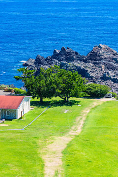 C&ocirc;te rocheuse et oc&eacute;an bleu vif au-del&agrave; d&rsquo;une pelouse en bord de mer