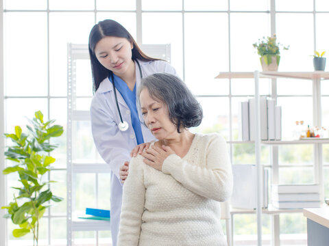 Asian female doctor physical therapist help senior woman back rehabilitation posture therapy in healthcare clinic professional patient care elderly recovery support wellness quality medical services.