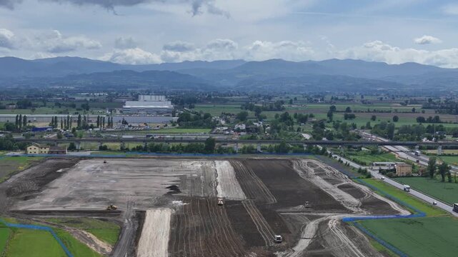 Logistics hub earthworks near Fiorenzuola d'Arda, Piacenza, Emilia-Romagna, Italy, revealing large construction site, soil grading, heavy machinery, the A1, A21 and SS9 corridor with Northern Apennine