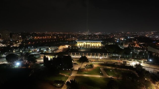 High angle perspective of the Knesset building and glowing city lights across Jerusalem at night.
