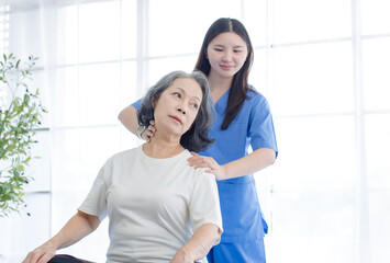 Fototapeta premium Asian female doctor physical therapist help senior woman back rehabilitation posture therapy in healthcare clinic professional patient care elderly recovery support wellness quality medical services.