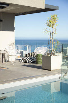 Rooftop terrace seating featuring two white woven chairs, striped cushions, pool and ocean view