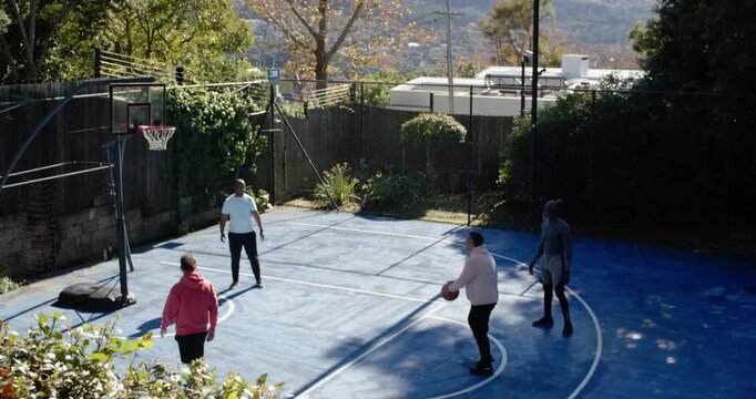 Diverse men practicing on private half-court at portable hoop, shooter preparing shot, scoring ball