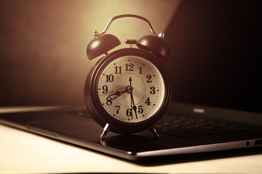 Alarm clock on laptop keyboard. Time management concept.