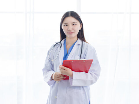 Portrait asian positive young woman doctor wearing white lab coat standing holding prescription folder in hospital clinic office  medical professional represents mission confidence trust patient care.