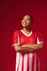 Fototapeta premium African American woman posing on red studio backdrop in red white striped jersey showing ear stud
