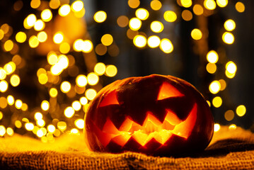 Spooky Halloween pumpkin lantern sitting on a table with warm bokeh background © Aliaksandr
