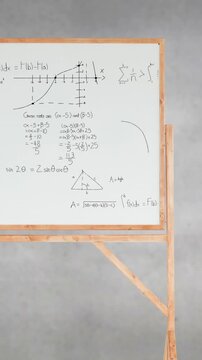 Pile of books and mathematical equations and graphs written in a white board